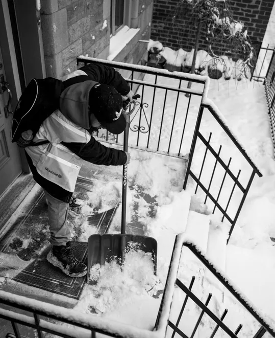 Une personne pelte le devant de sa porte enneigé